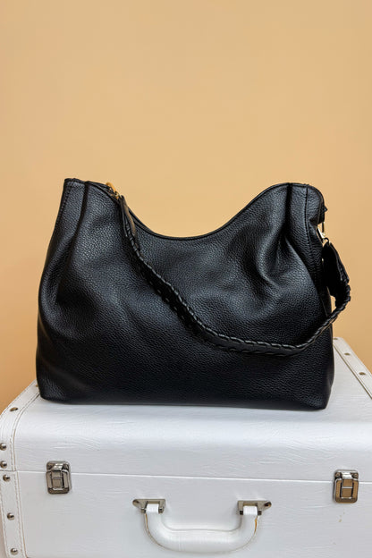 Black handbag on a white suitcase with a beige background
