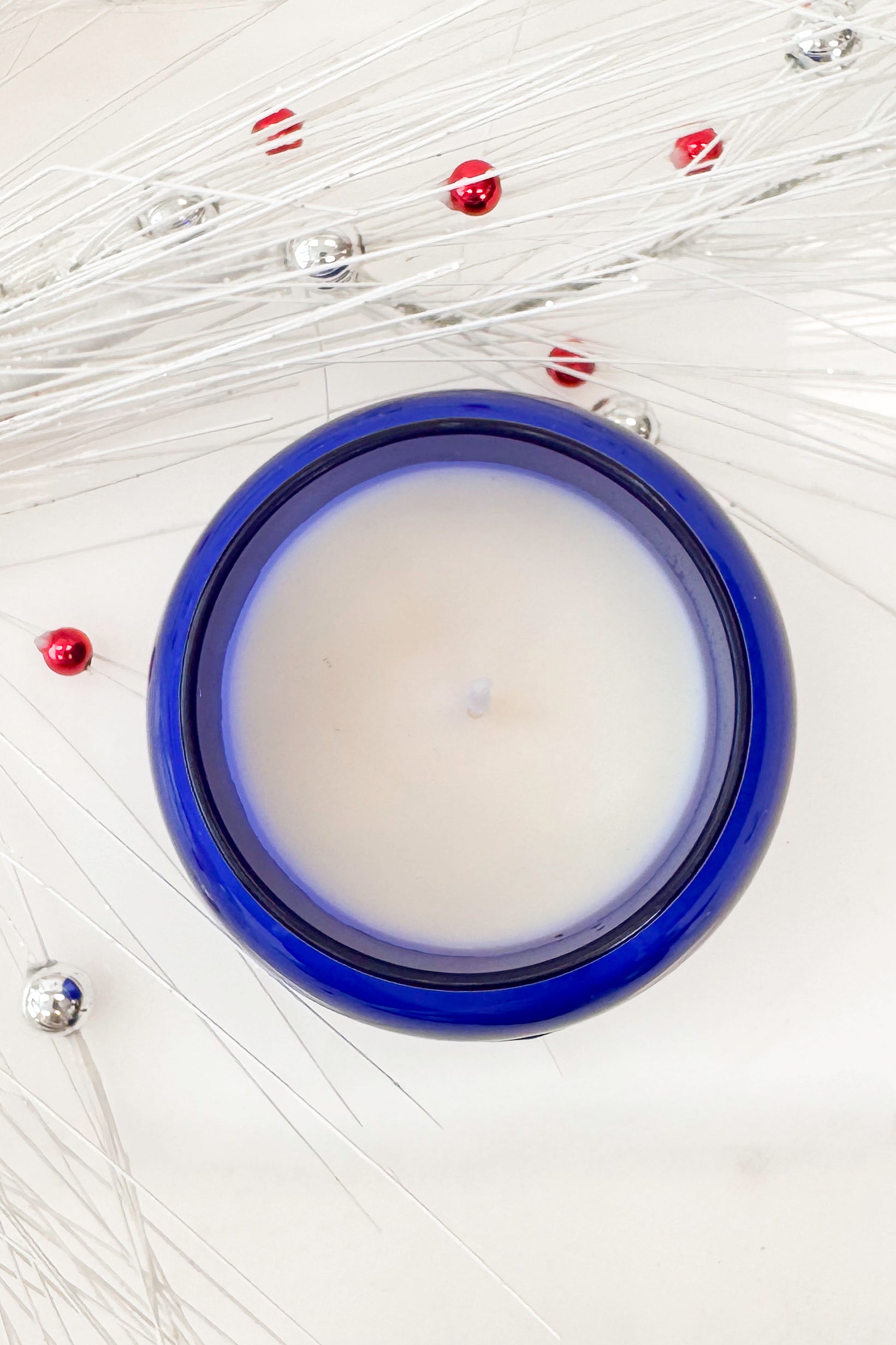 Blue candle jar with silver lid on a white background