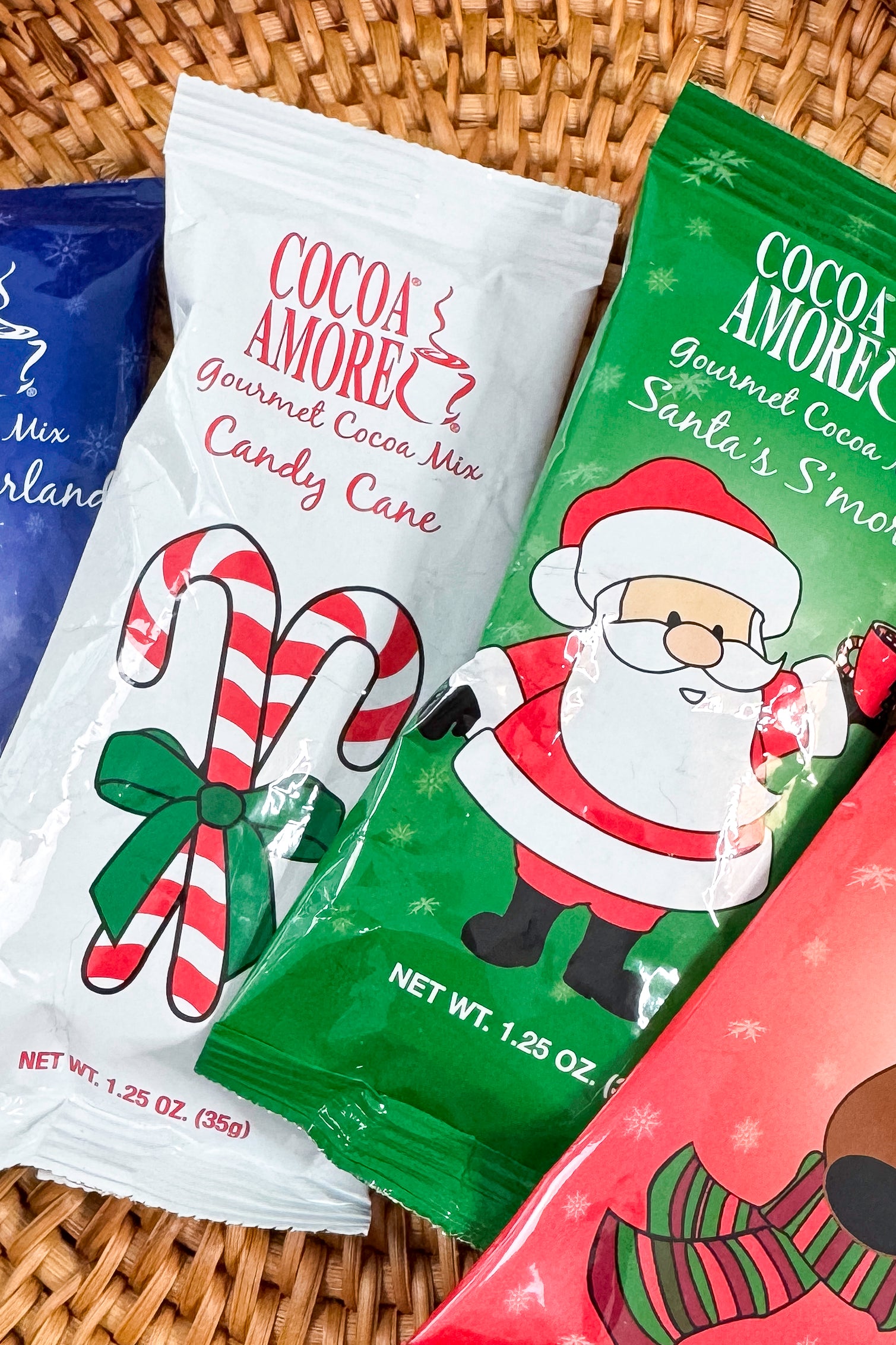 Close up of Cocoa Amore Gourmet Cocoa Mix packages with illustrations on a patterned background.