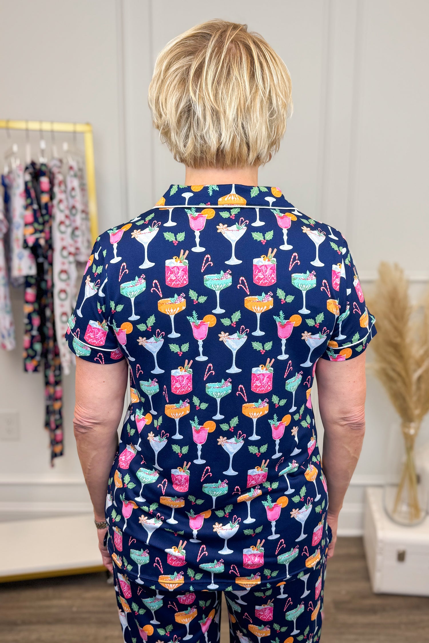 Person wearing a navy pajama set with colorful cocktail pattern in a room.