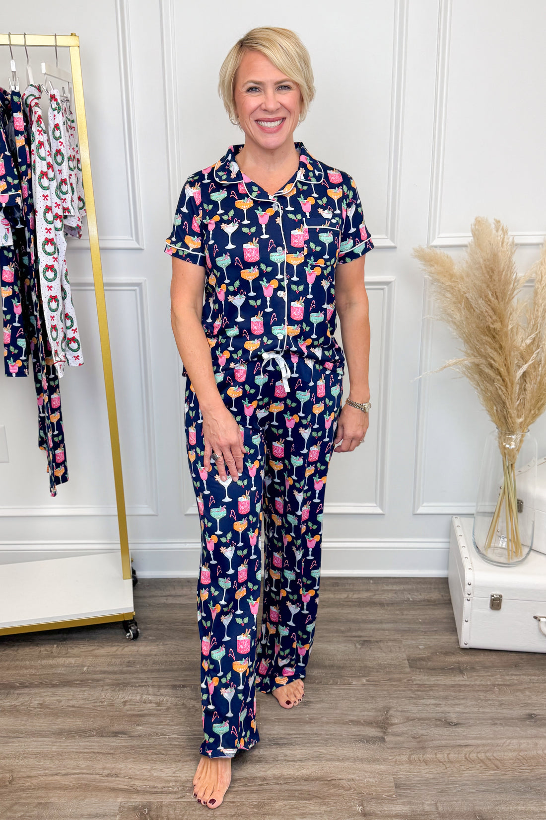 Woman wearing a navy pajama set with colorful pattern in a room with a clothing rack and decorative elements.