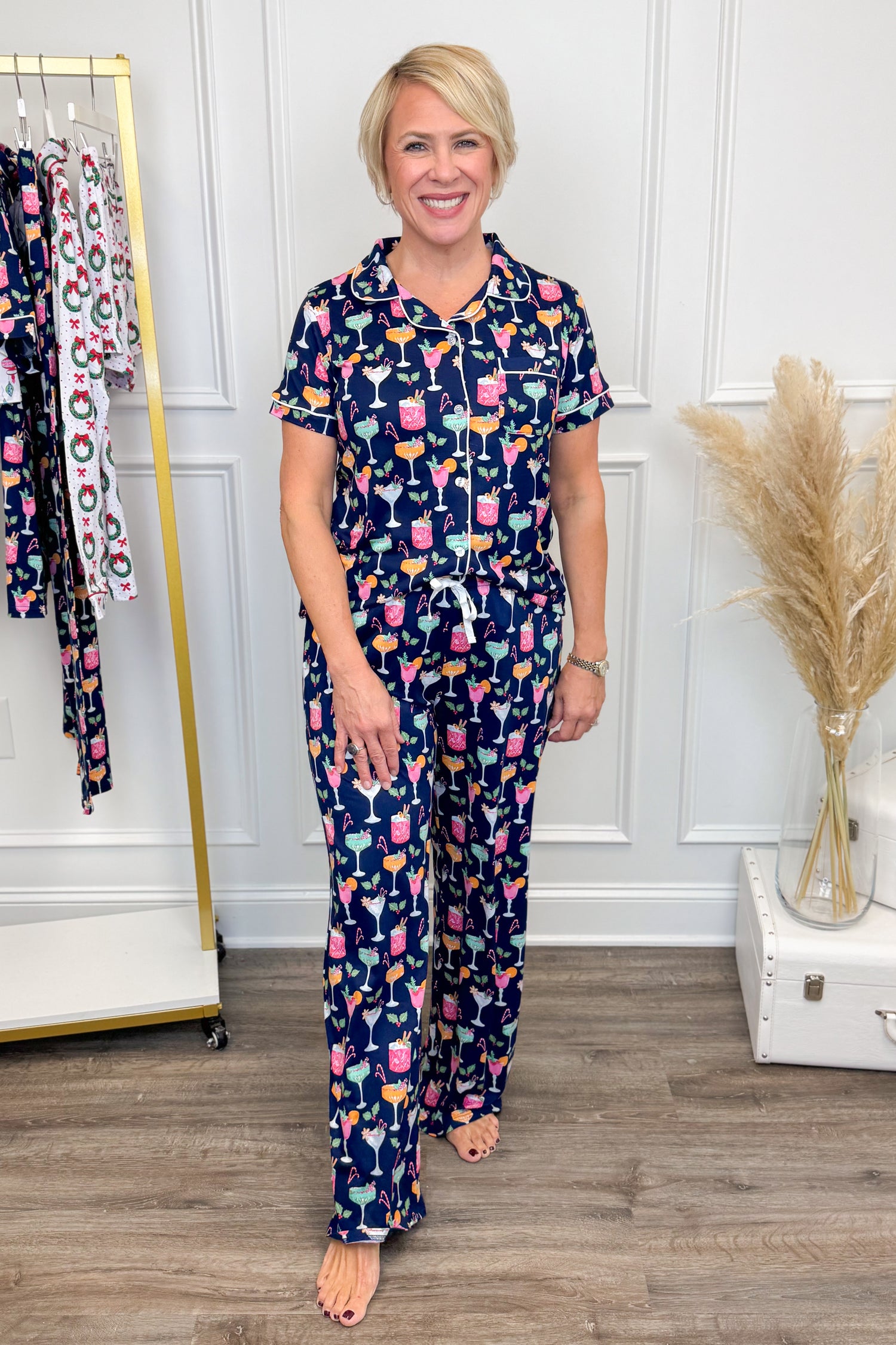 Woman wearing a navy pajama set with colorful pattern in a room with a clothing rack and decorative elements.