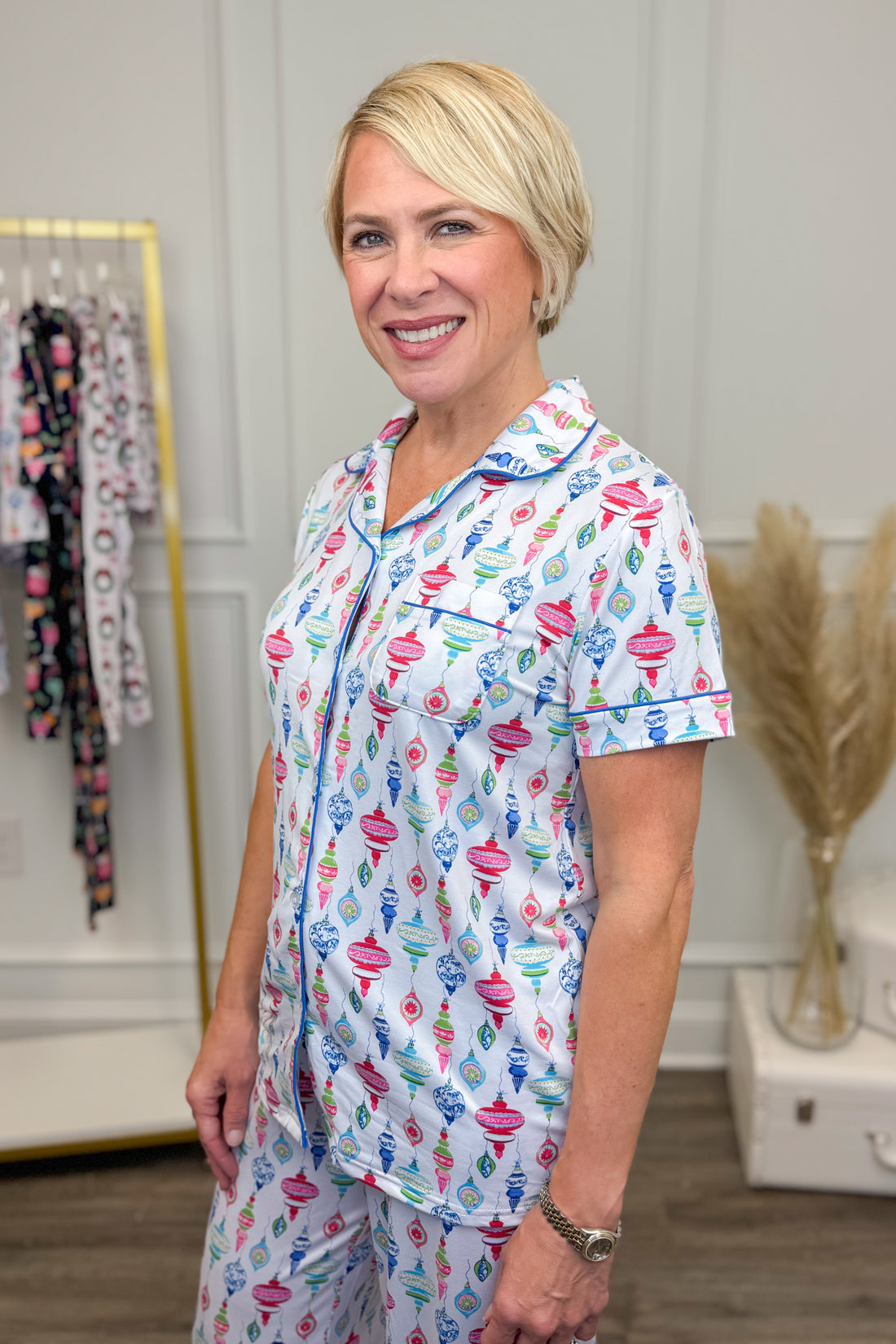 Woman wearing a colorful pajama set in a room with clothing racks.