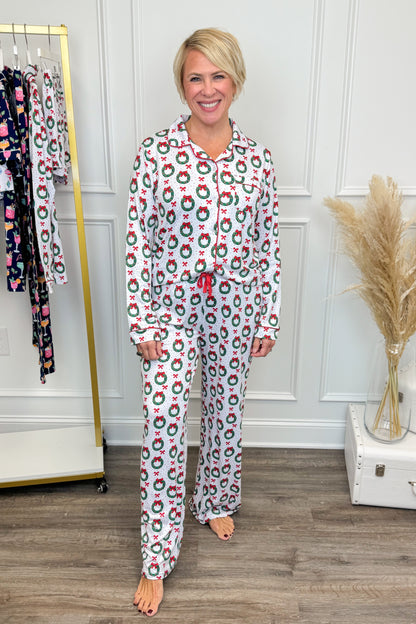 Woman wearing a festive pajama set in a room with a clothing rack and decorative items.