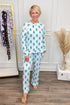 Woman wearing a patterned pajama set in a room with a rack of clothes and decorative elements.