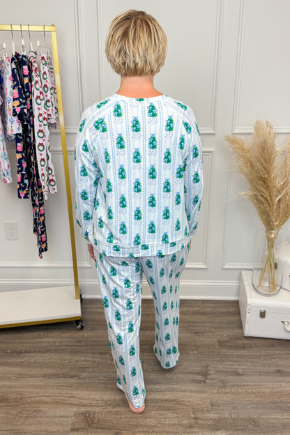 Woman wearing a patterned pajama set in a room with a rack of clothes and decorative elements.