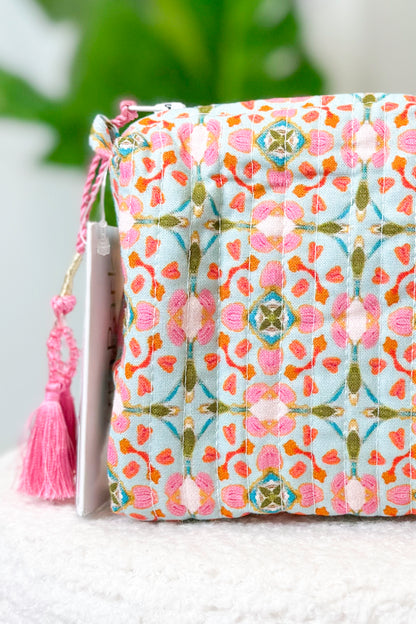 Fabric pouch with floral pattern and pink tassel on a white surface