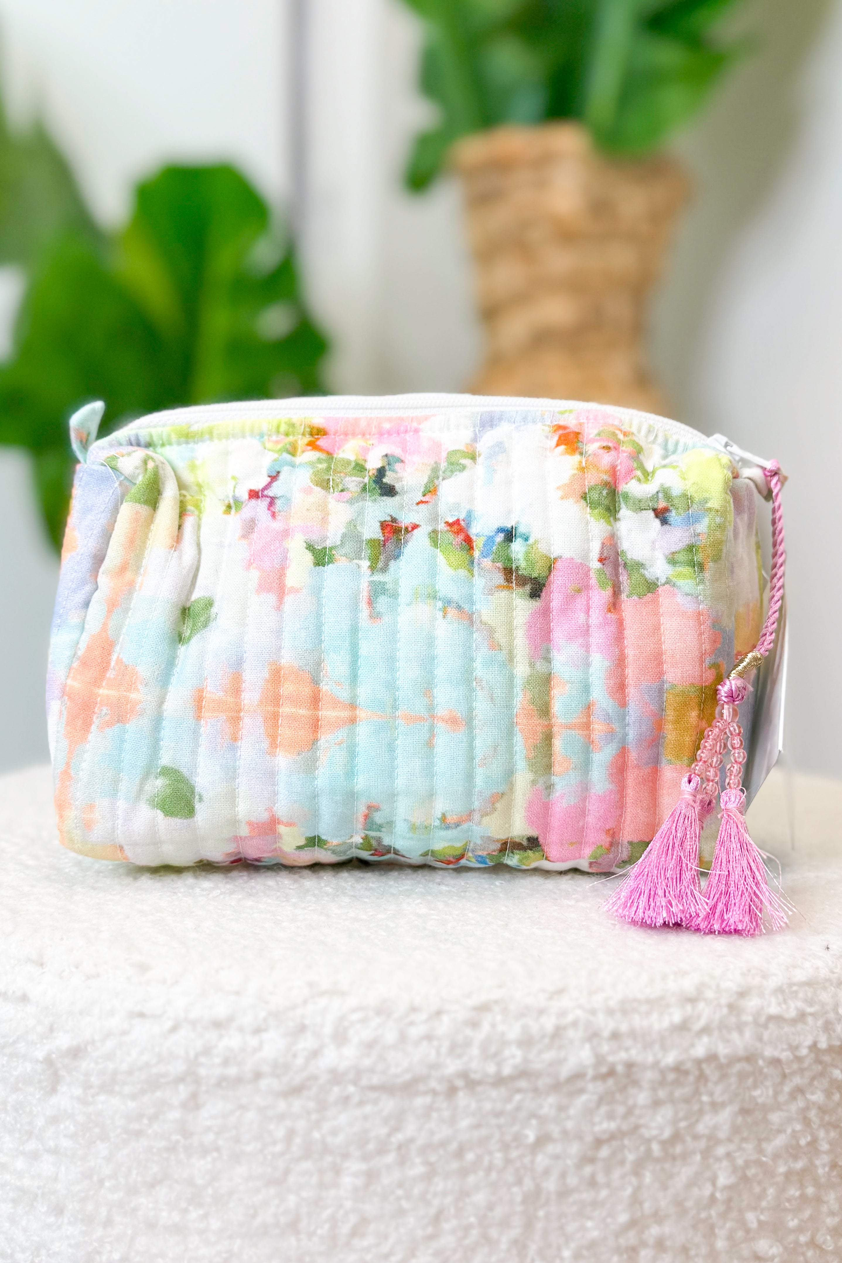 Floral patterned pouch with a tassel on a textured surface