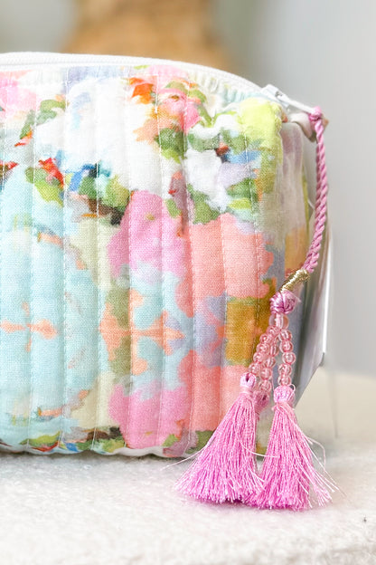 Floral-patterned clutch bag with a pink tassel on a light background