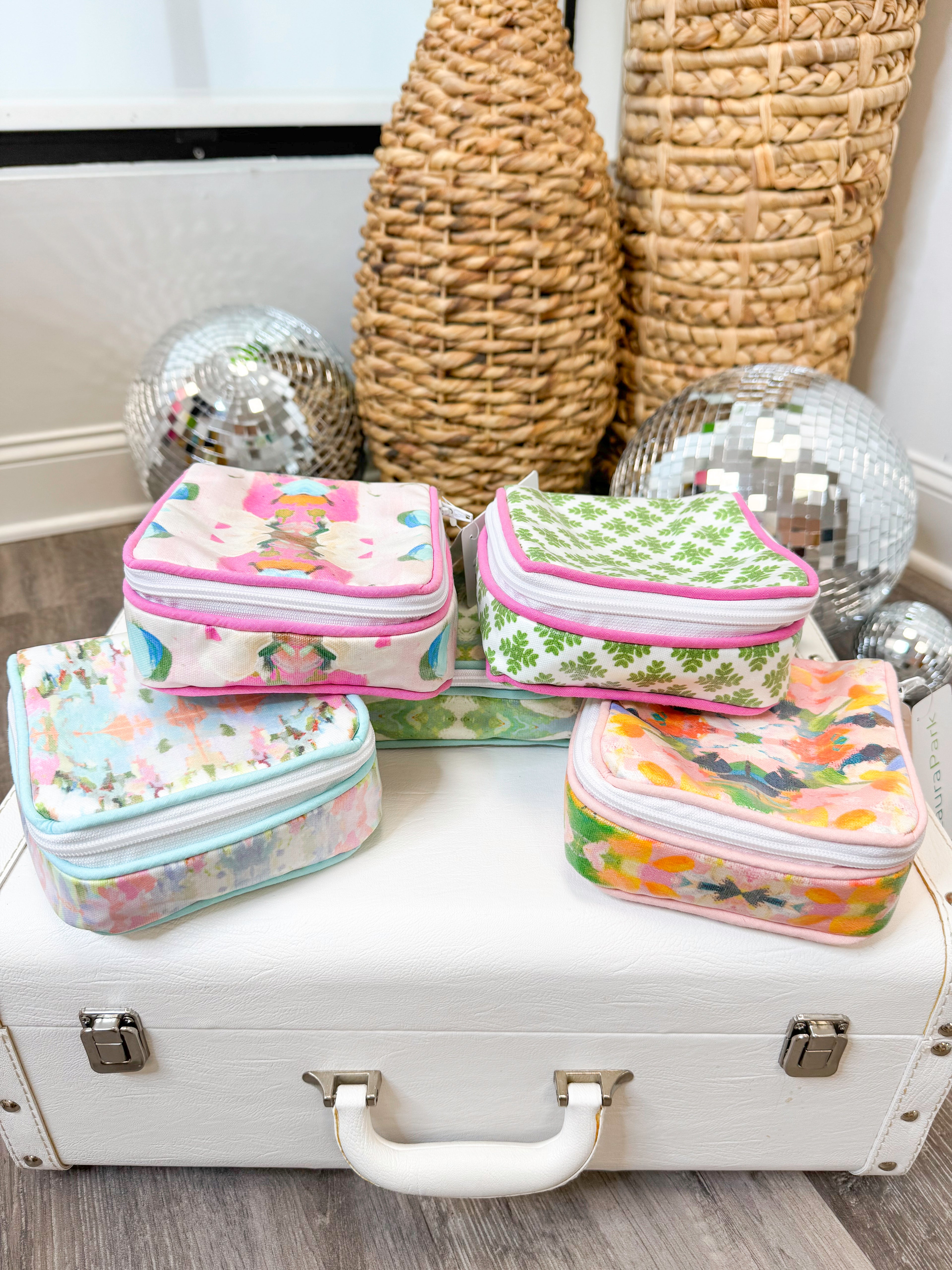 Set of colorful small rectangular bags on a white suitcase with decorative vases and disco balls in the background.