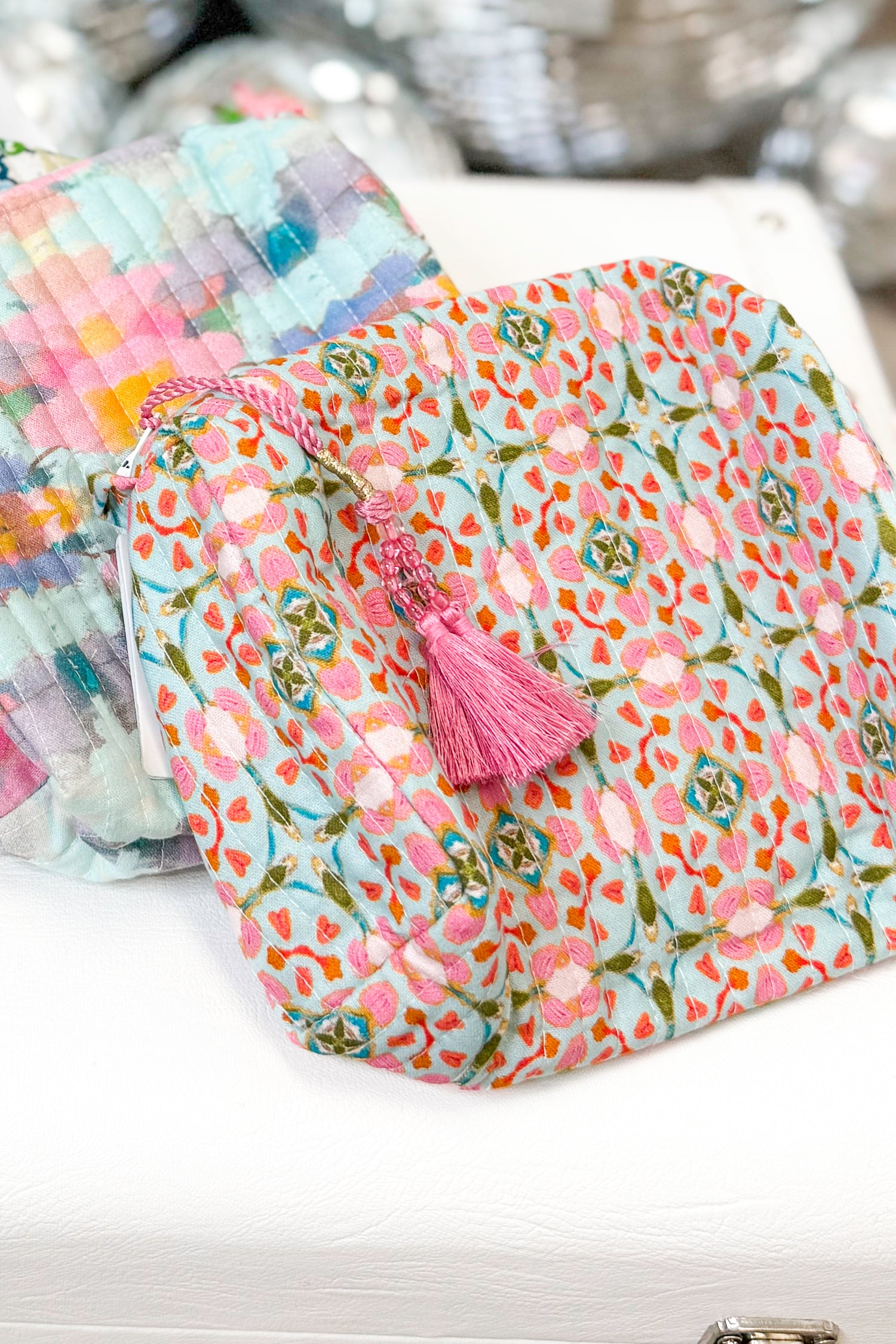 Floral patterned pouch with a pink tassel on a white surface