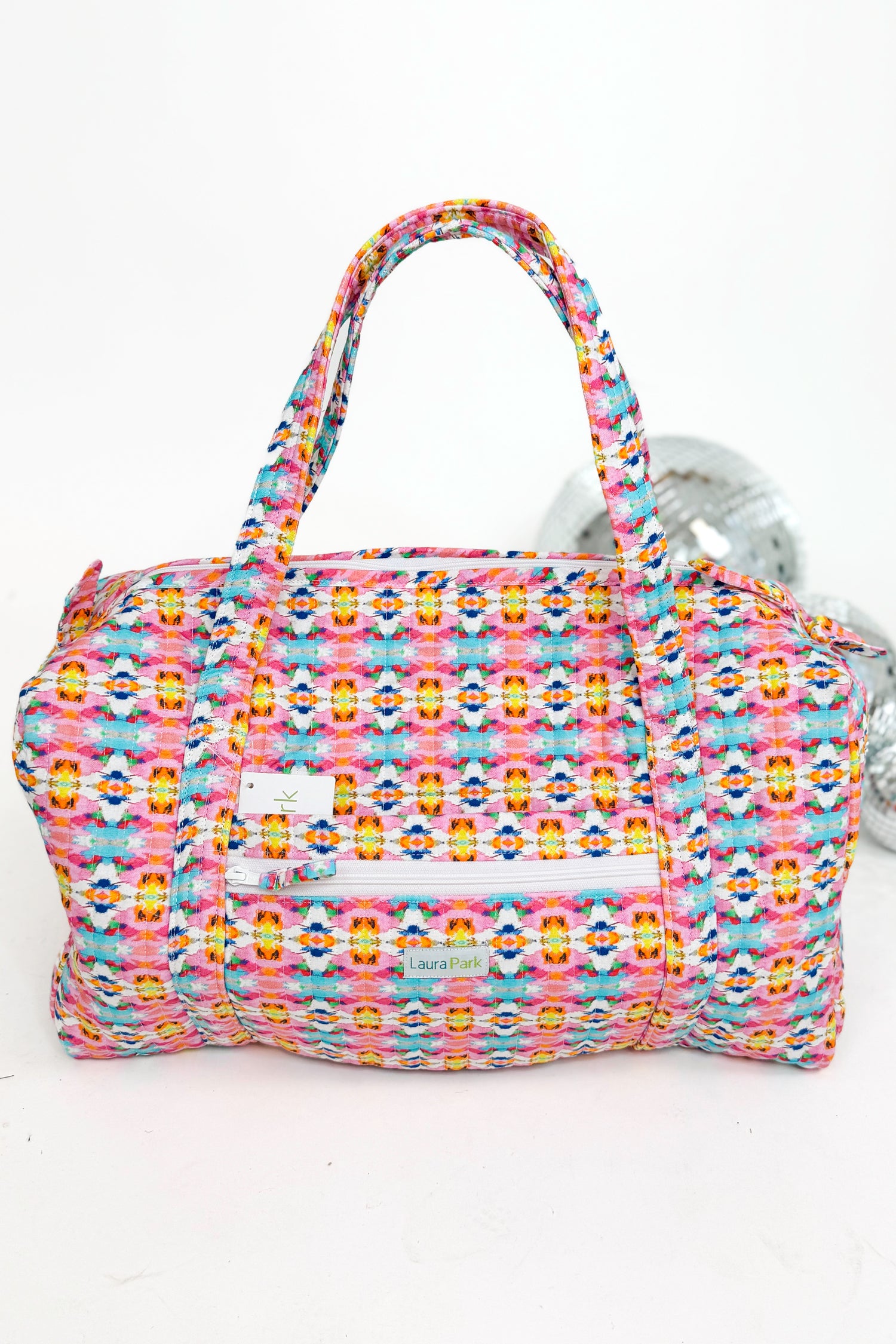 Multicolored patterned handbag with a visible brand label on a white background