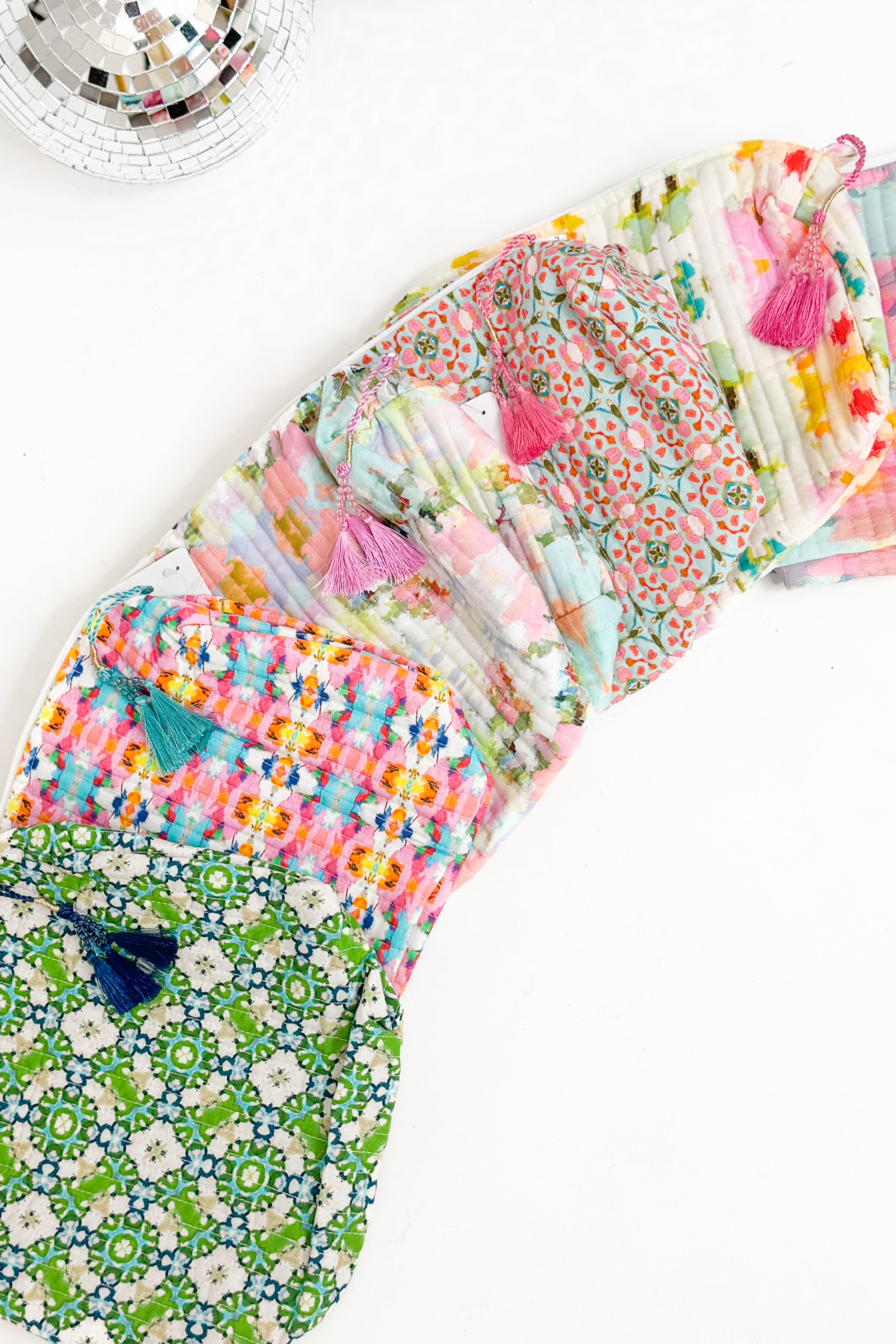 Collection of colorful fabric bags with tassels on a white background