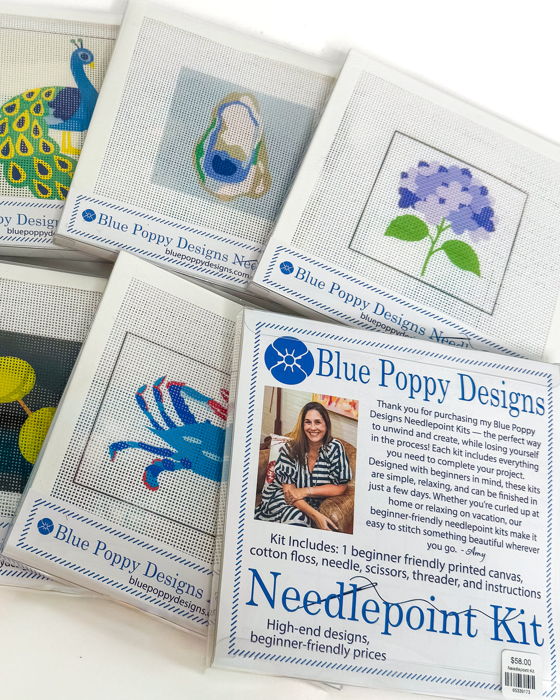 Collection of Blue Poppy Designs needlepoint kits on a white surface
