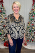 Front view of woman wearing Black With Velvet Pattern Top with jeans with holiday decor in the background.