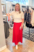 Front view of woman wearing cream top with Festive Red Northpointe Midi Skirt at a boutique.
