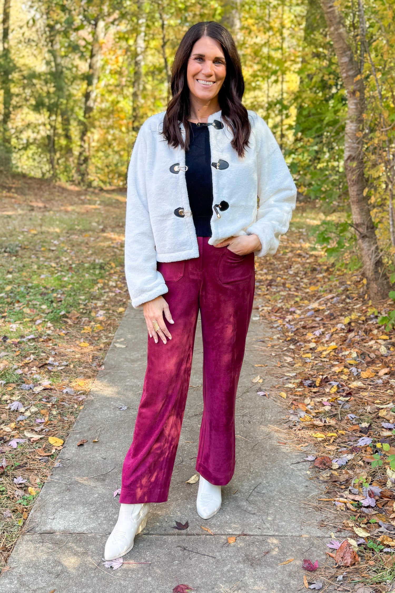 Front view of woman wearing Cream Faux Fur Toggle Button Jacket with Burgundy Suede Wide Leg Pants outside.