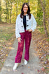Front view of woman wearing Cream Faux Fur Toggle Button Jacket with Burgundy Suede Wide Leg Pants outside.