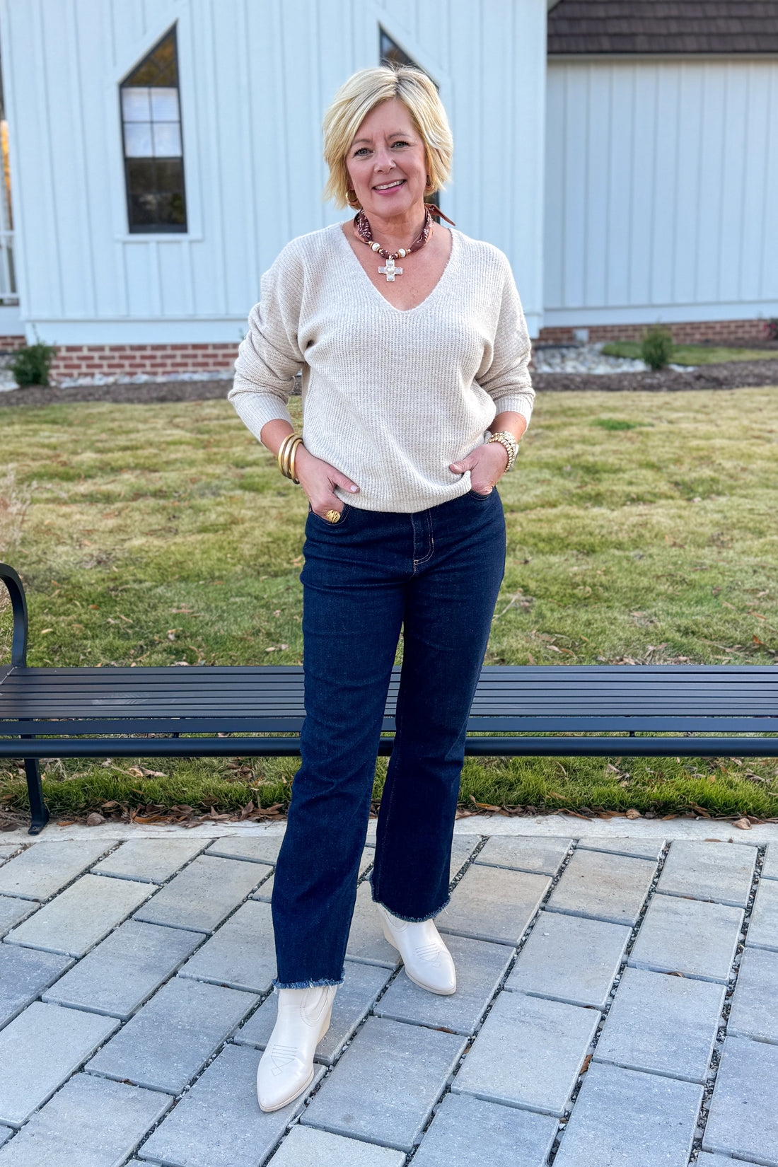 Woman standing outdoors on a patio with a white building in the background
