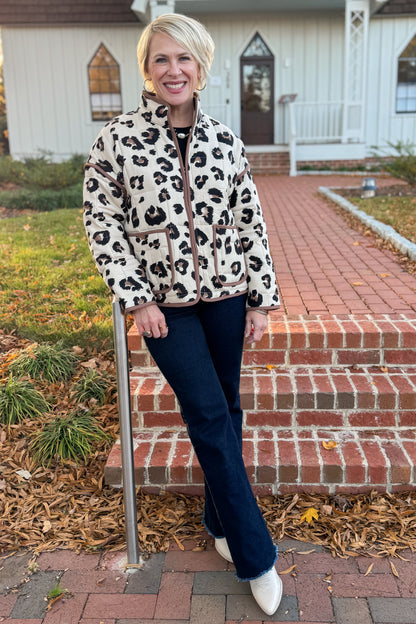 Woman wearing a leopard print jacket standing on steps outside a house.