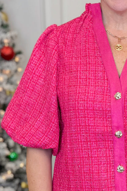 Woman in a pink jacket standing in front of Christmas trees with decorations.