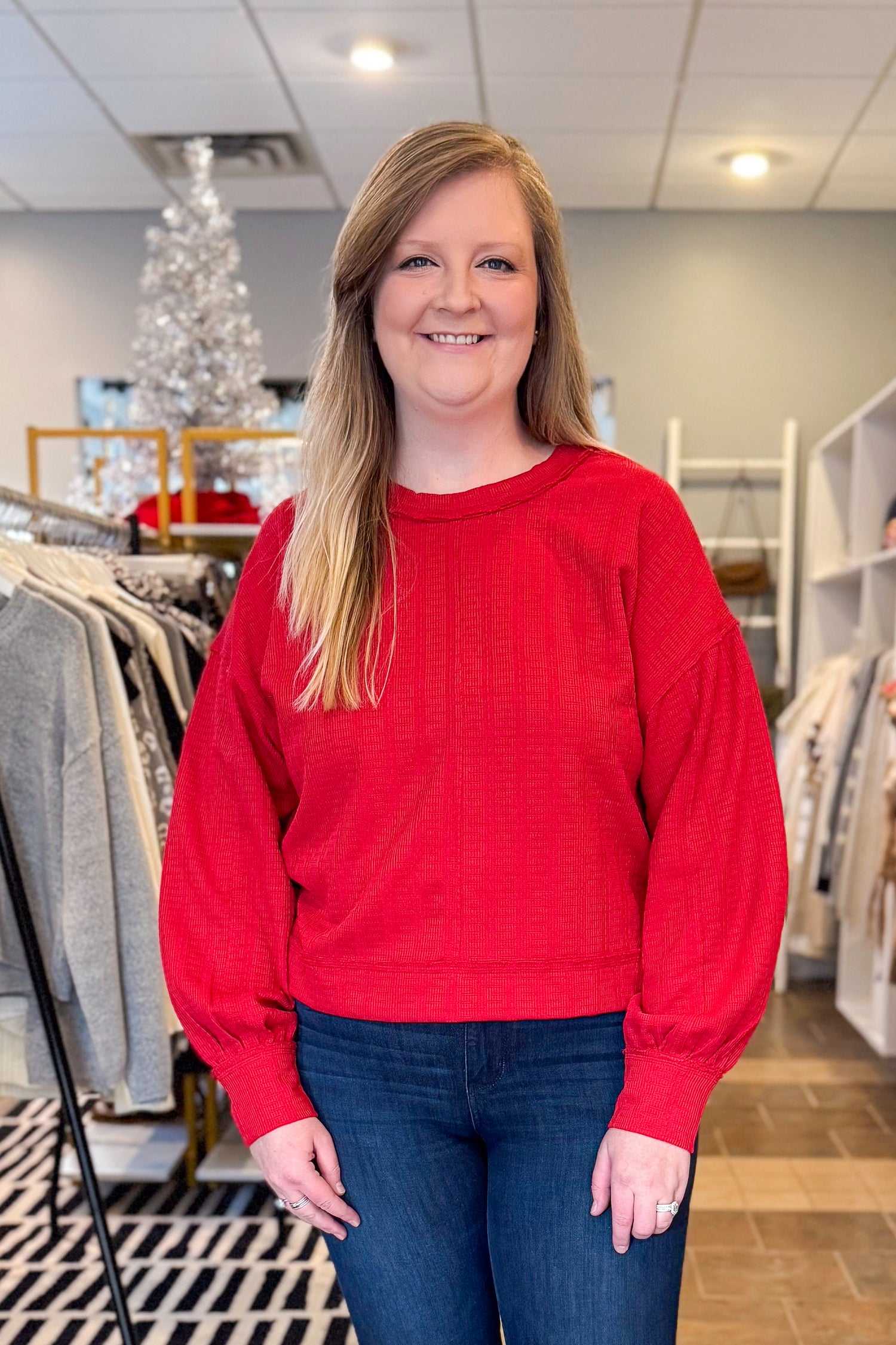 Front view of woman wearing Red Center Seam Textured Top with jeans at a boutique.