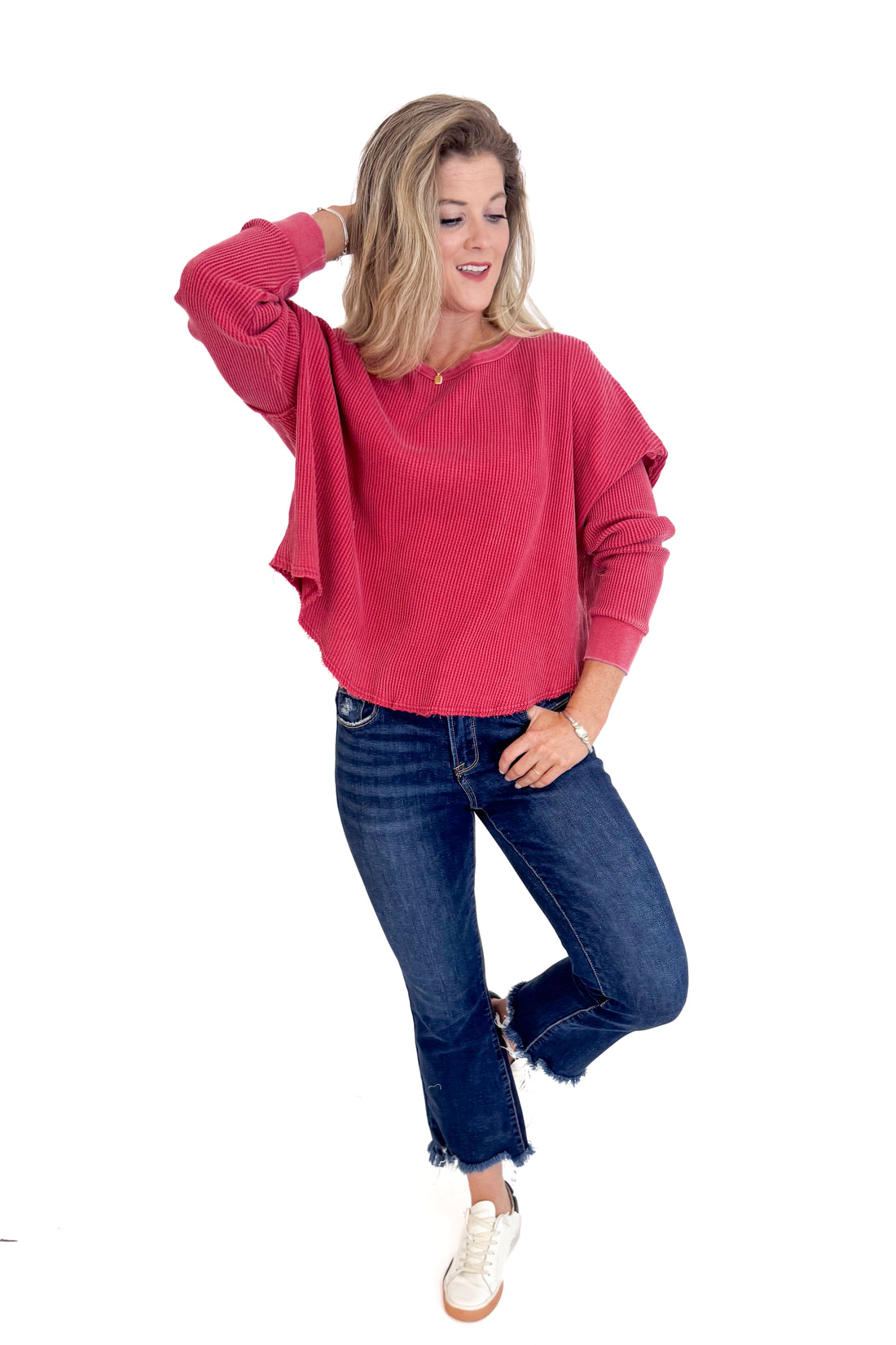 Woman wearing a red sweater and blue jeans on a white background