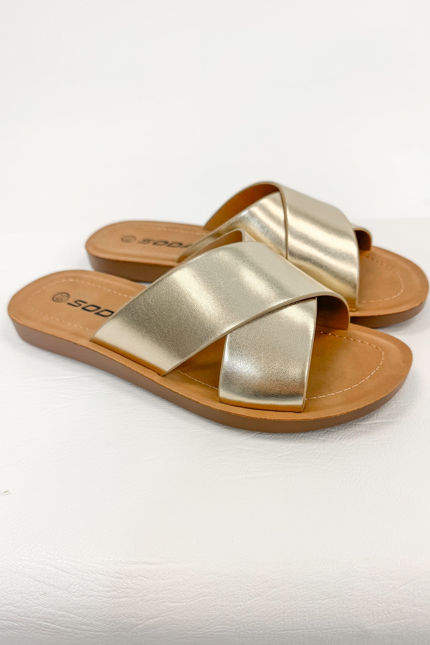 Reflect- Gold Cross Strap Sandals against white studio background side view.