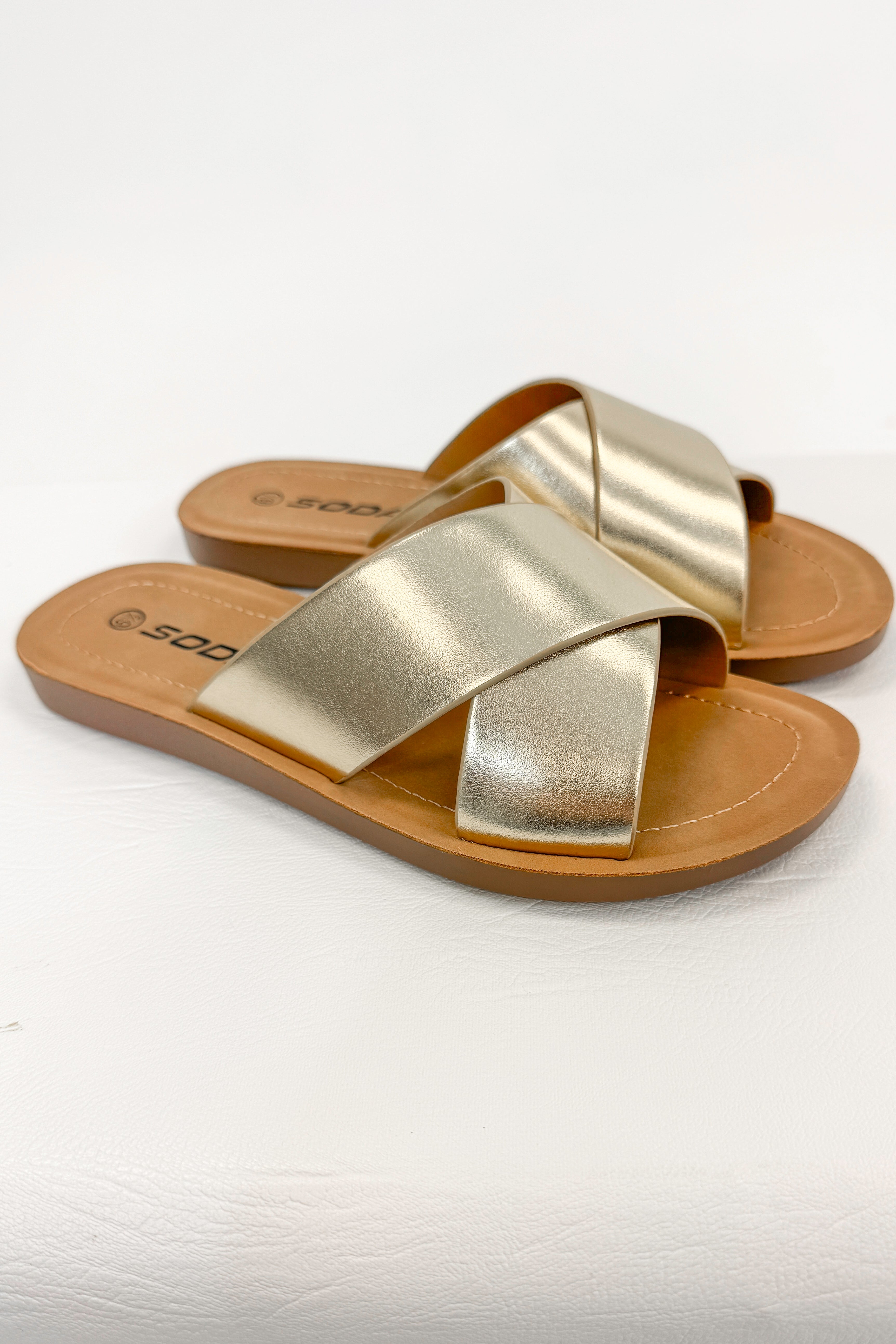 Reflect- Gold Cross Strap Sandals against white studio background side view.