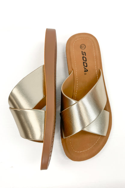 Reflect- Gold Cross Strap Sandals against white studio background