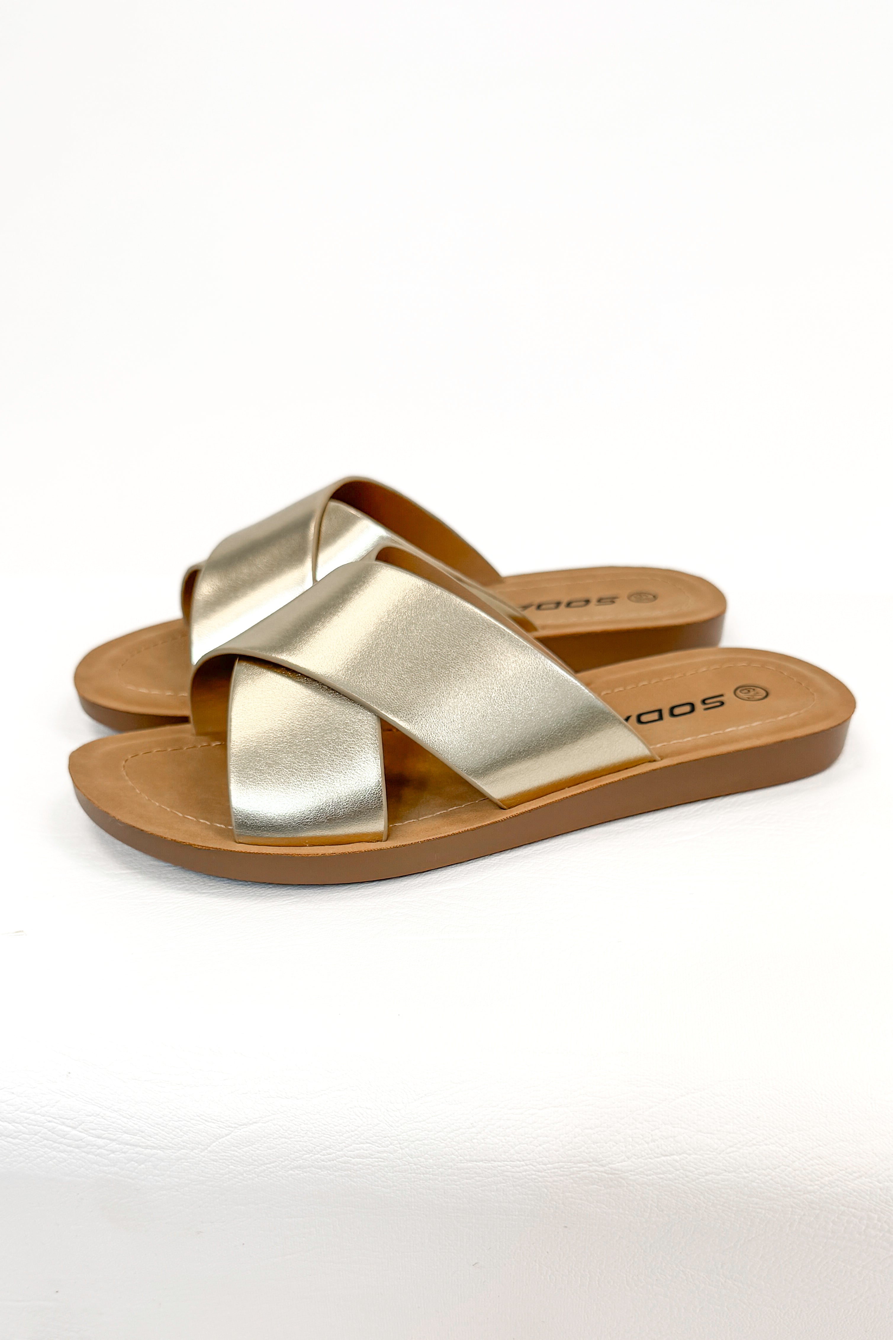 Reflect- Gold Cross Strap Sandals against white studio background side view.