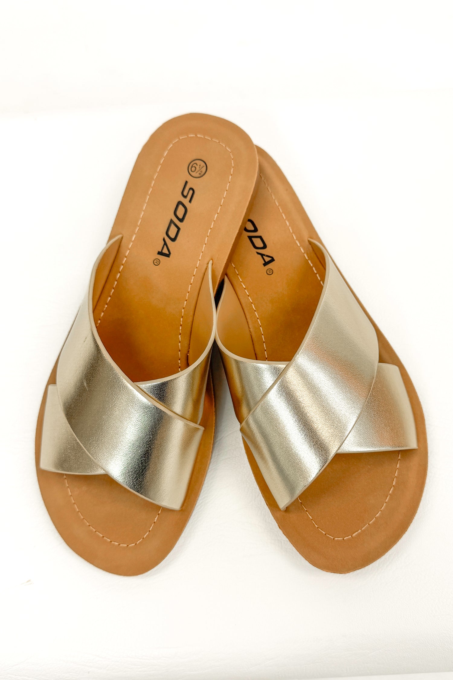 Reflect- Gold Cross Strap Sandals against white studio background top view.