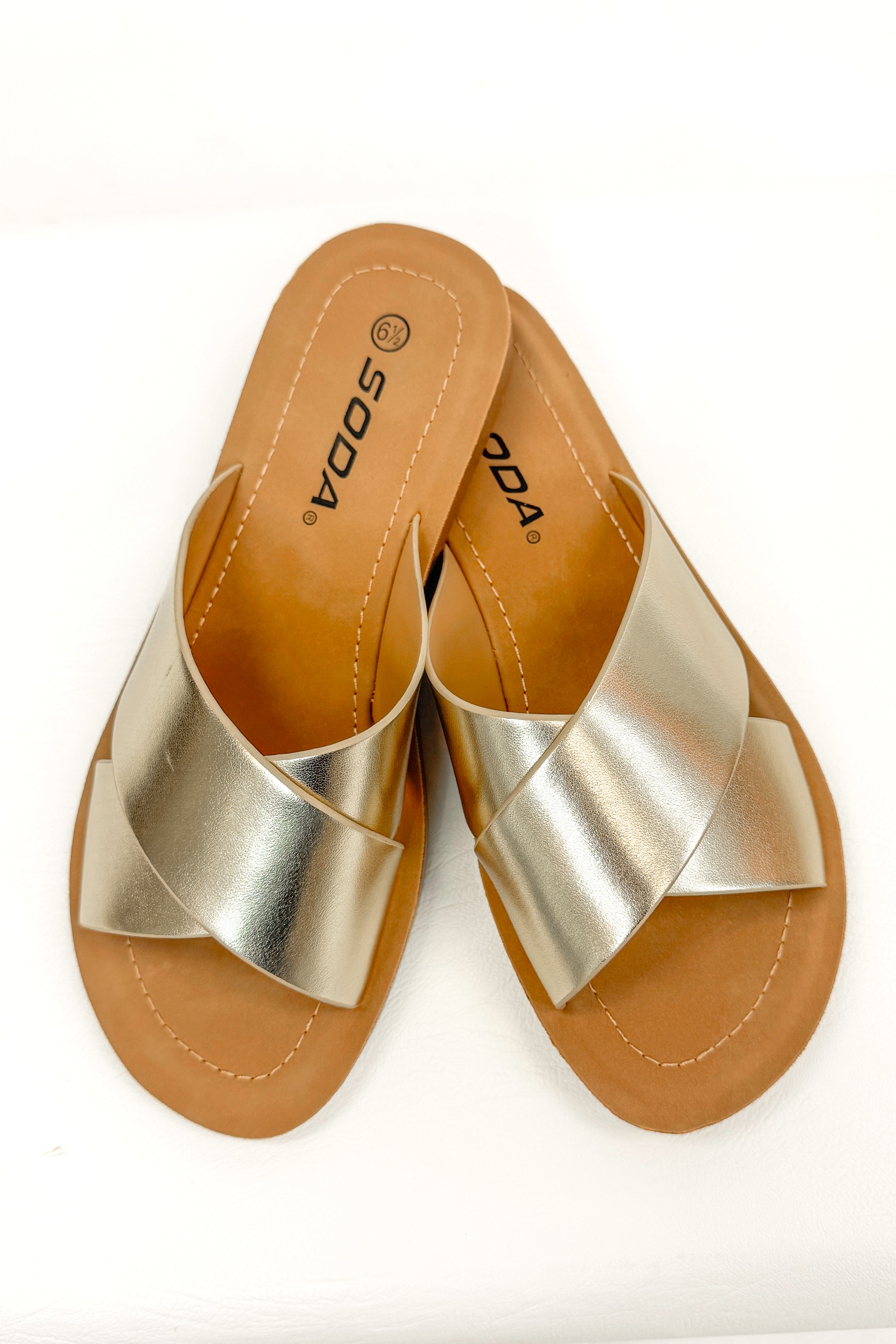 Reflect- Gold Cross Strap Sandals against white studio background top view.