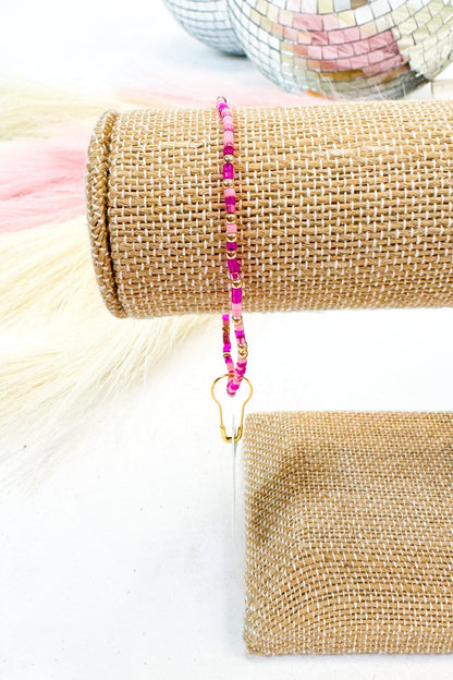 Beaded bracelet with pink beads displayed on a textured surface.