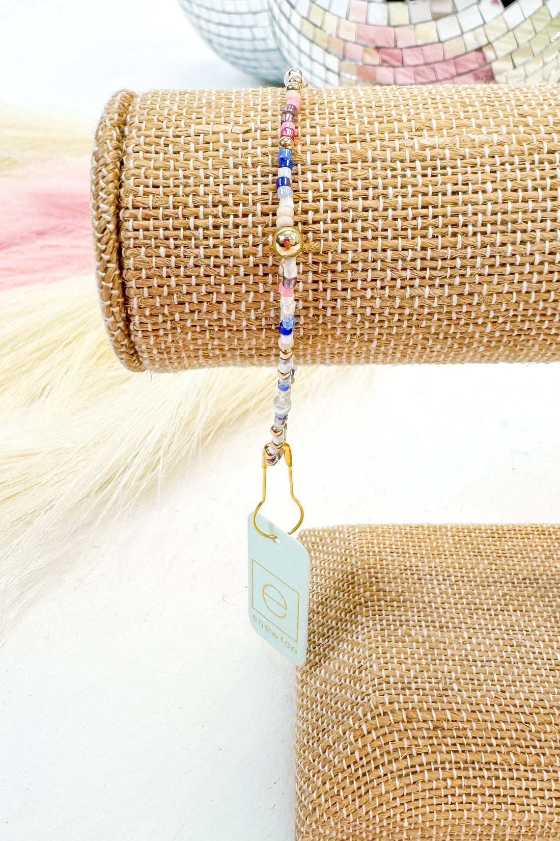 Beaded bracelet on a textured surface with a visible brand tag.