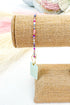 Roll of burlap with a colorful beaded bracelet on top, against a neutral background.