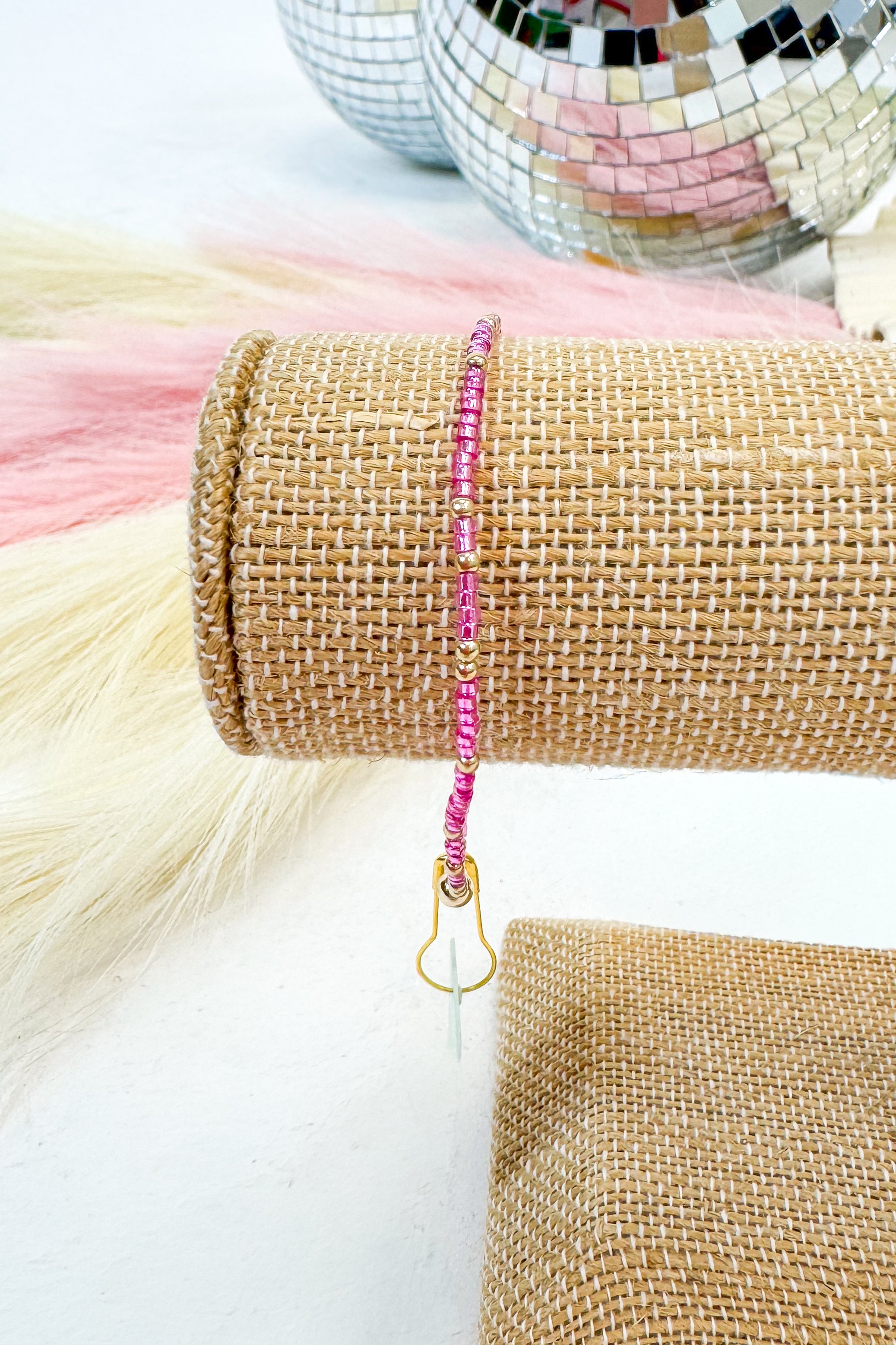 Pink beaded lanyard on a roll of burlap with disco balls in the background