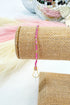 Pink beaded lanyard on a roll of burlap with disco balls in the background