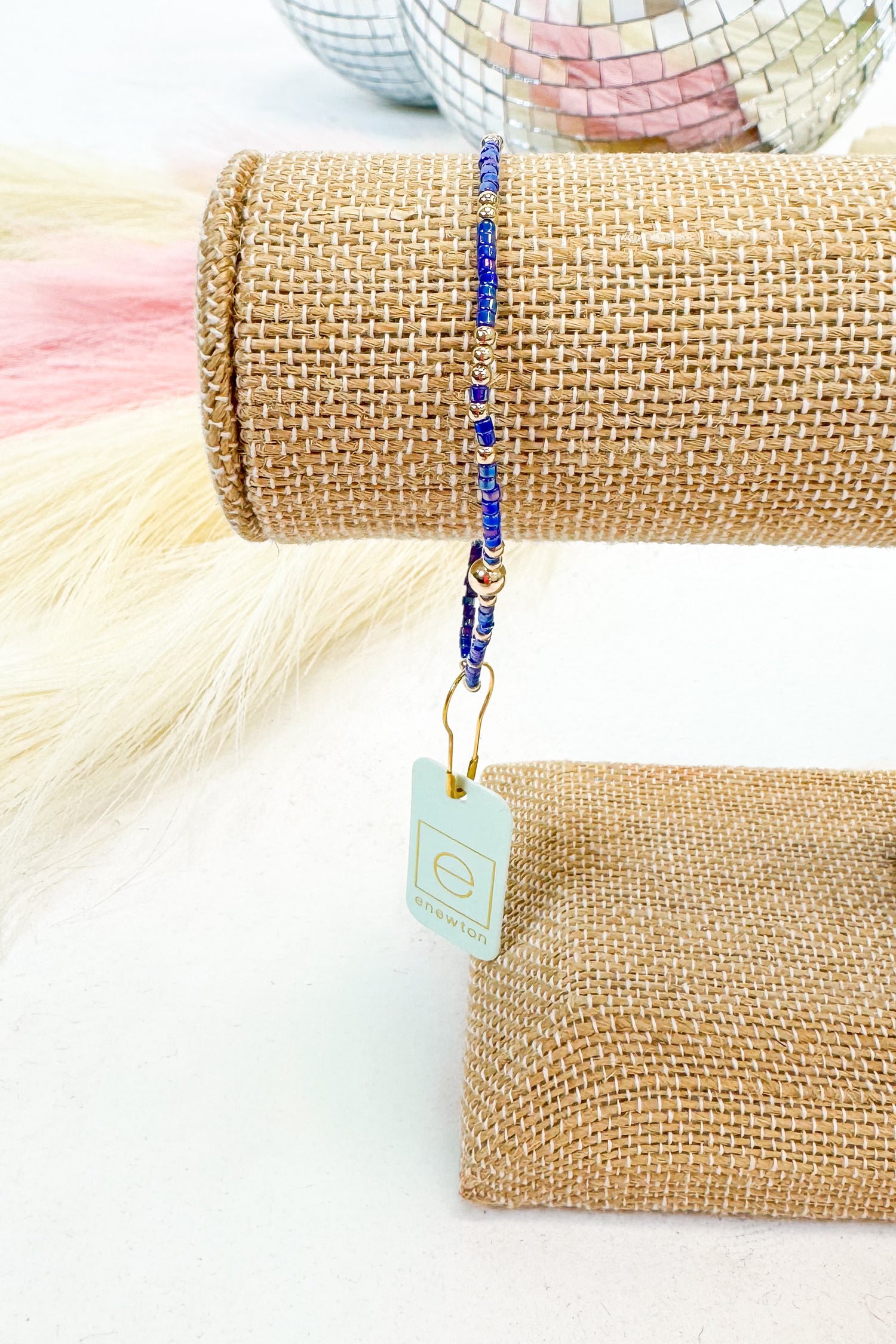 Beaded bracelet on a roll of burlap with a tag, on a white background