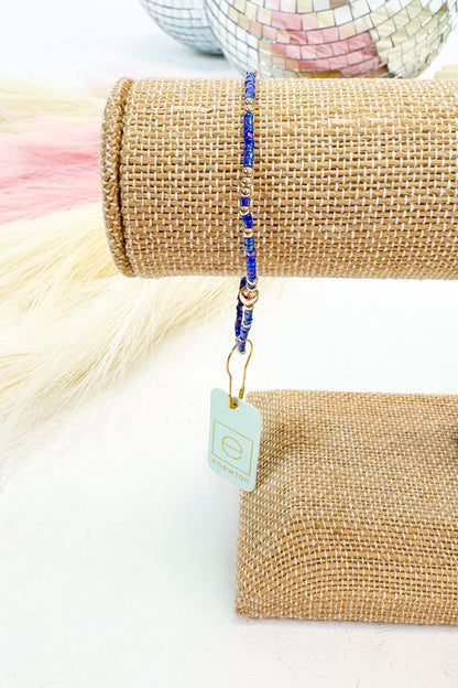 Beaded bracelet on a roll of burlap with a tag, on a white background