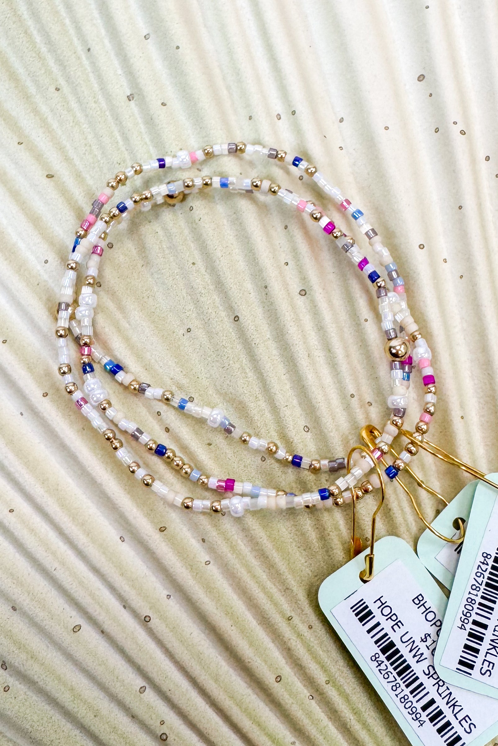 Colorful beaded necklace with tags on a beige fabric background