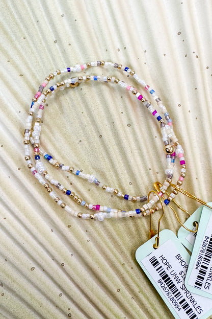 Colorful beaded necklace with tags on a beige fabric background