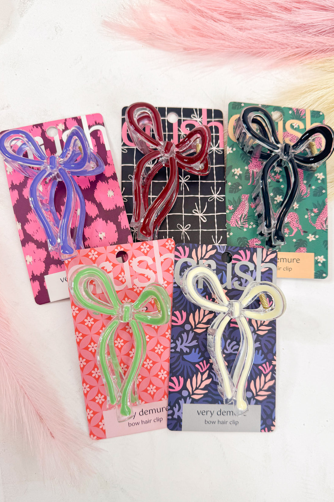 Set of bow-shaped hair clips on branded cards with a soft pink background