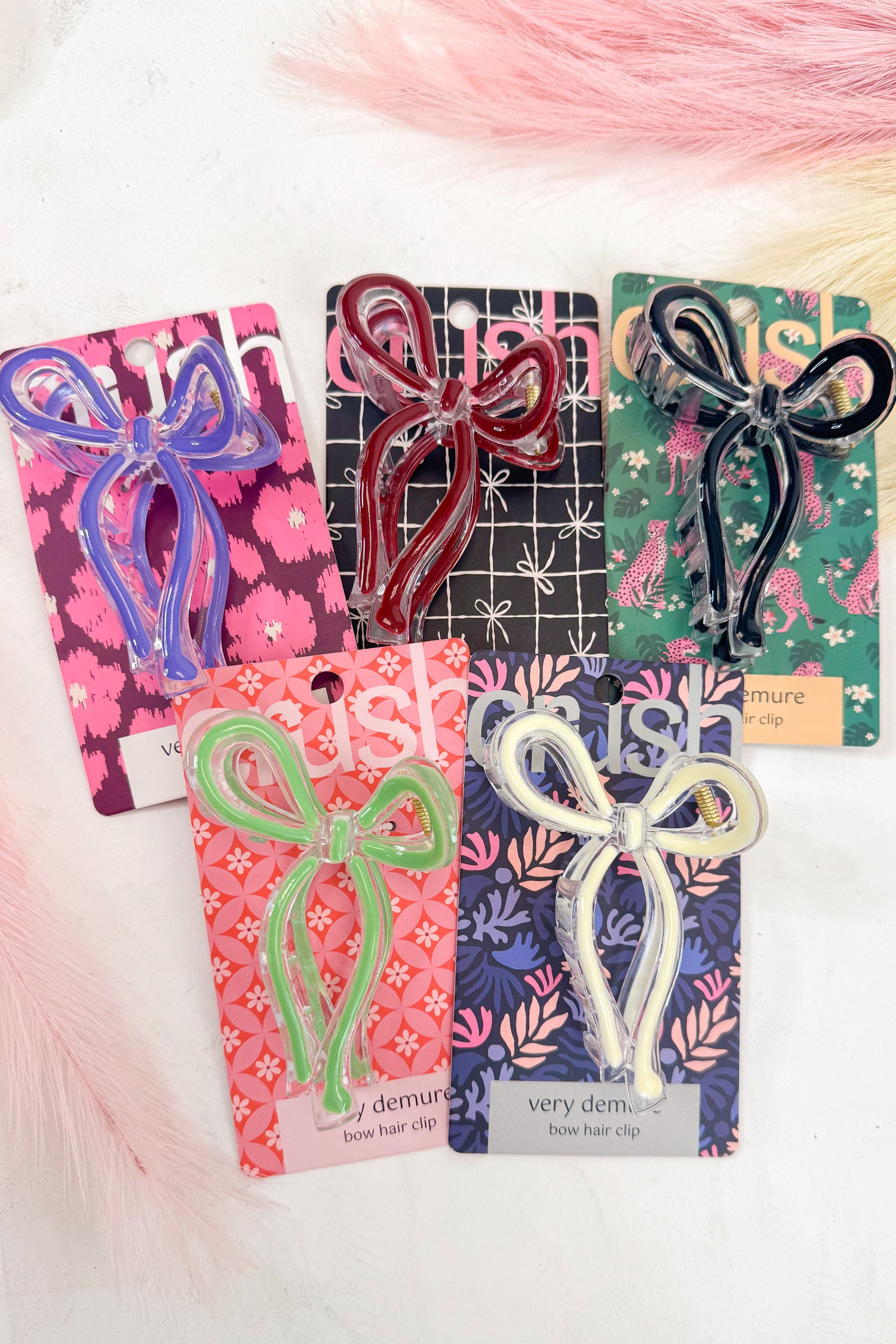 Set of bow-shaped hair clips on branded cards with a soft pink background
