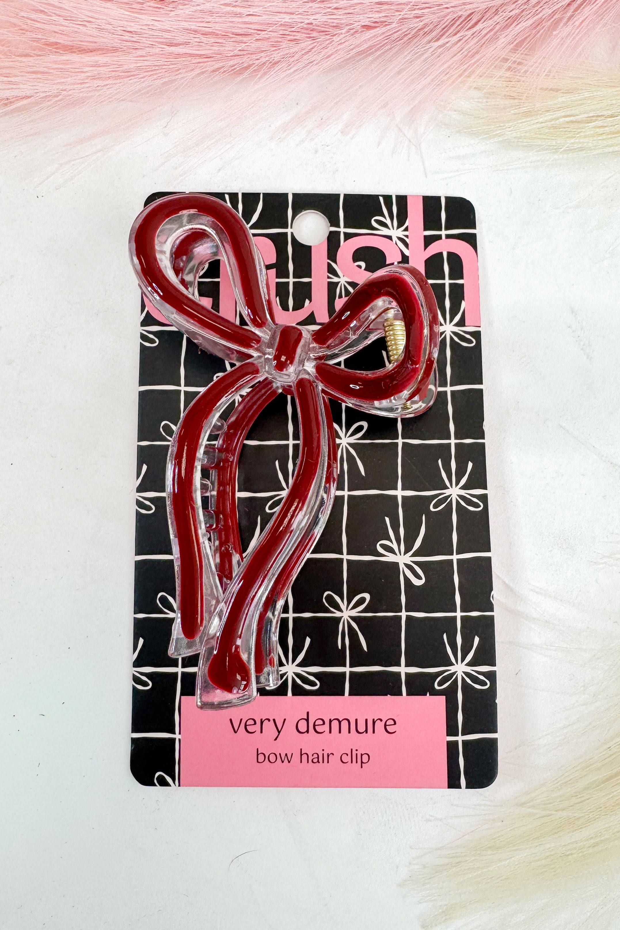 Red bow hair clip on a black and white patterned card with &
