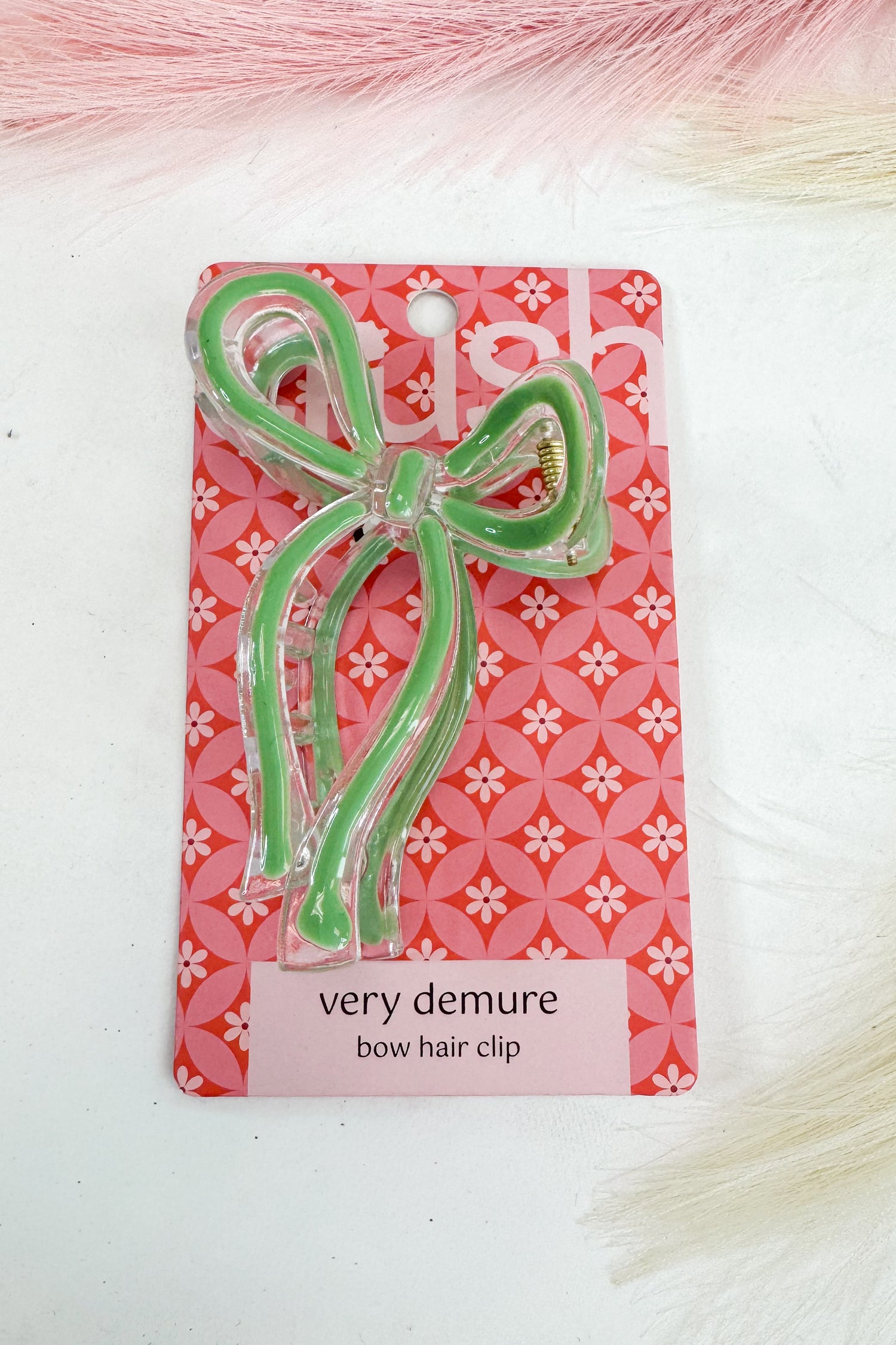 Green bow hair clip on a pink floral patterned card with &