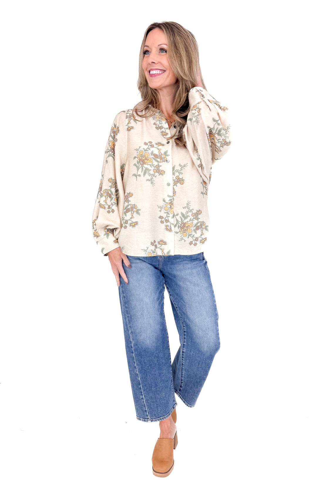Woman wearing a floral blouse and blue jeans on a white background