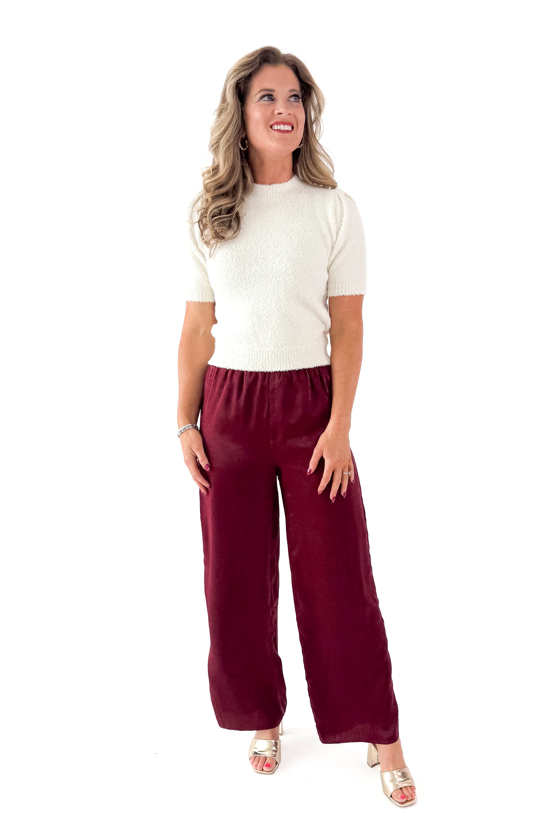 Front view of woman wearing cream sweater and Wine Satin Wide Leg Pants against white studio background.