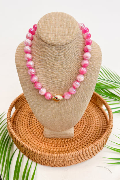 Necklace with pink beads on a brown bust against a white background
