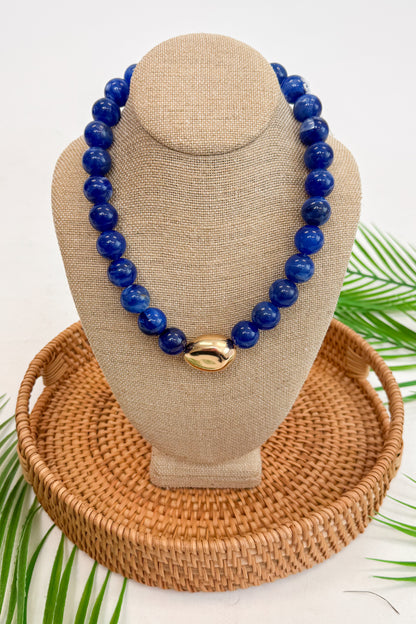 Dark blue beaded necklace on a beige mannequin bust with a woven base.